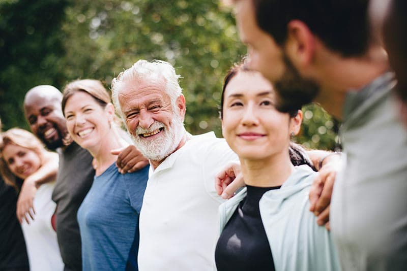 A group of adults standing together outdoors with their arms around one another