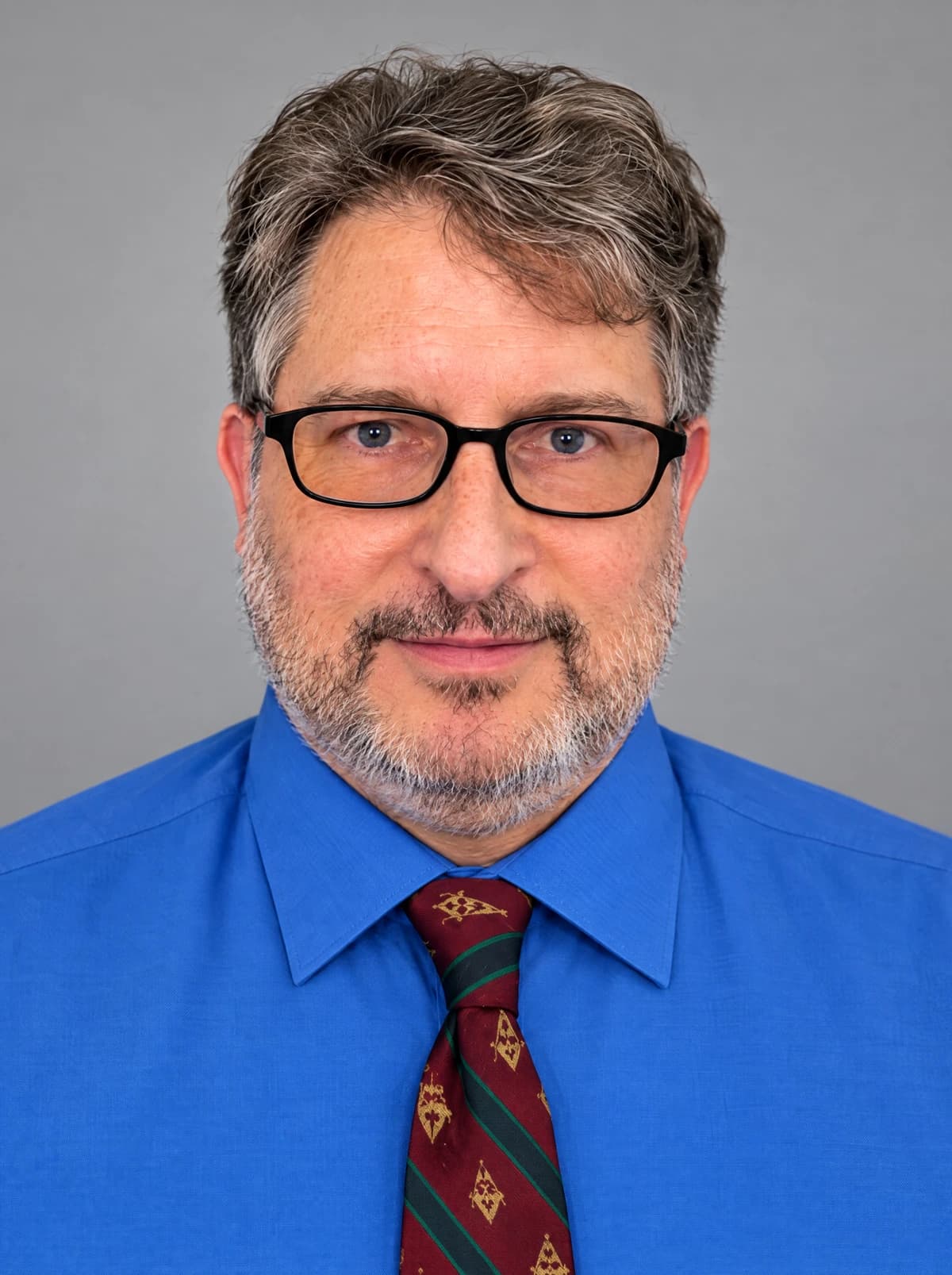 Dr. James “Jim” Staudenmeier wearing black glasses, a blue shirt and a red patterned tie