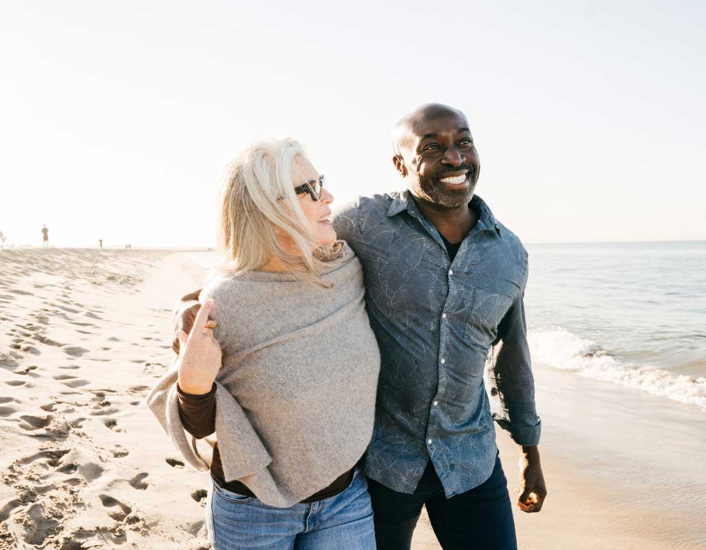 A couple walking together along a sunny beach