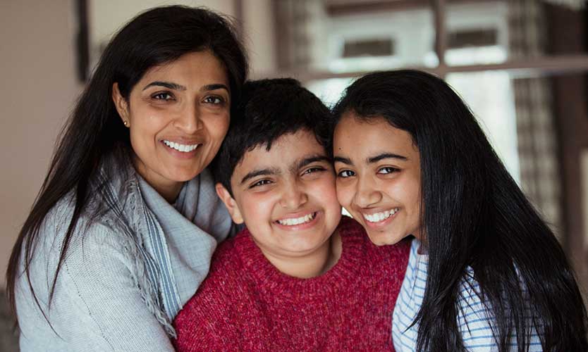 A woman and two children smiling and embracing